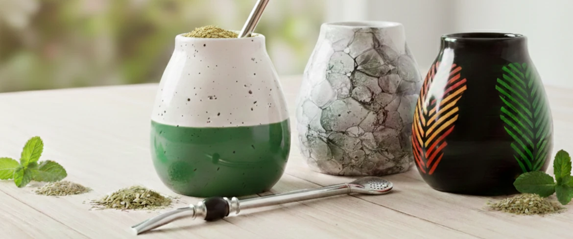 Accesorios para la yerba mate: diferentes tazas para yerba mate y una bombilla sobre una mesa de madera.
